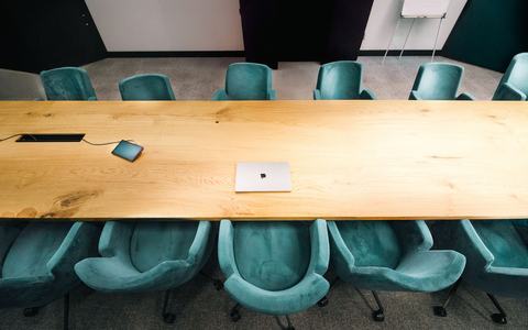 Empty boardroom with a long wooden table and teal chairs