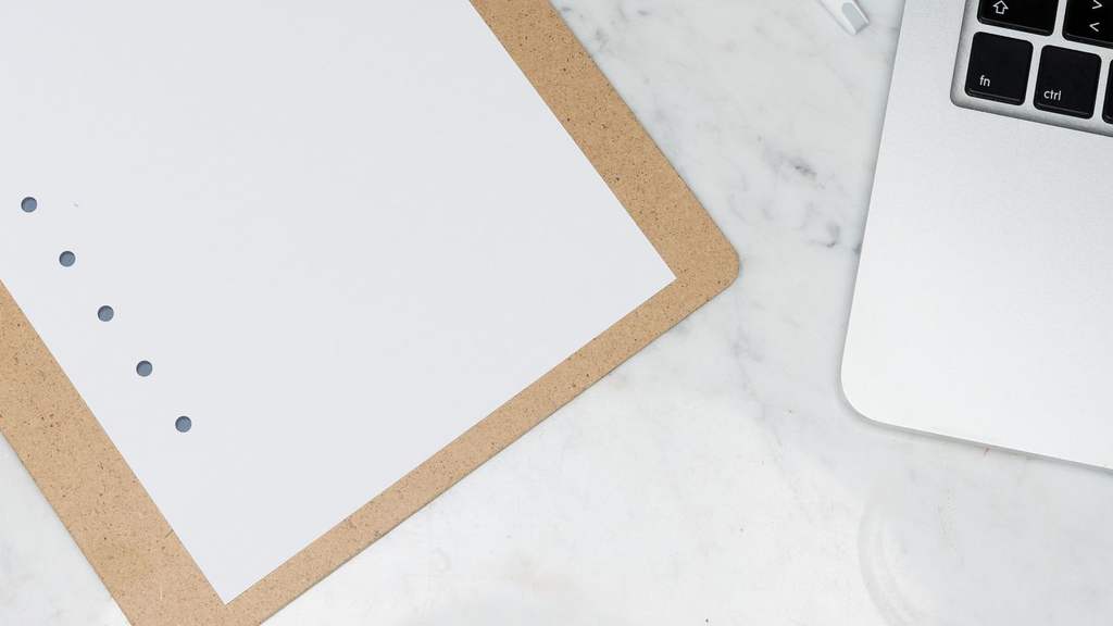 Clipboard checklist, pen and laptop on a marble desk