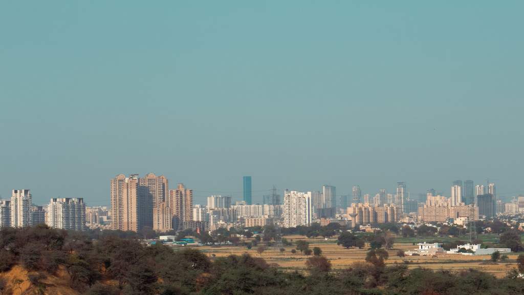 Gurugram skyline in Delhi-NCR beyond the green Aravalli scrub and a curving road