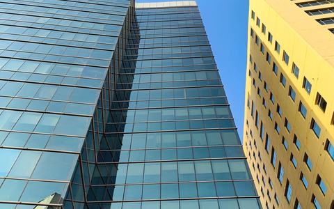 Glass office tower in Gurugram, India, reflecting a clear blue sky