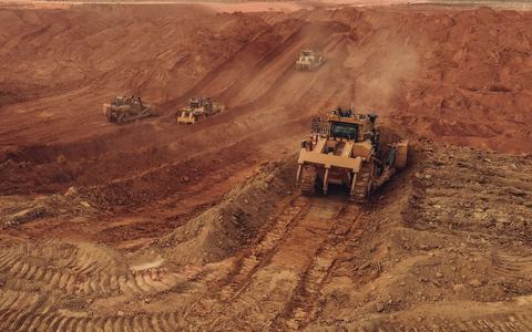 Heavy earth-moving equipment working on red soil at an open-pit mine, seen from above
