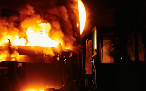 Molten metal pouring in a steel plant at night, glowing orange