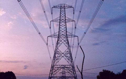 High-voltage power transmission tower and lines against a blue sky